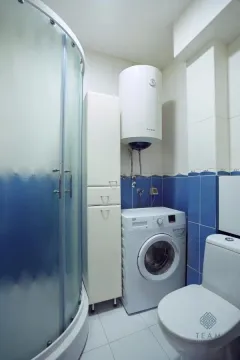 Bathroom with a shower cabin, washing machine, and water heater. - image 10