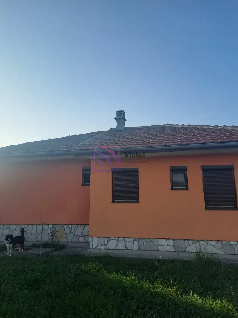 Pogled na zadnju stranu kuće sa fasadom narandžaste boje i popločanim krovom.