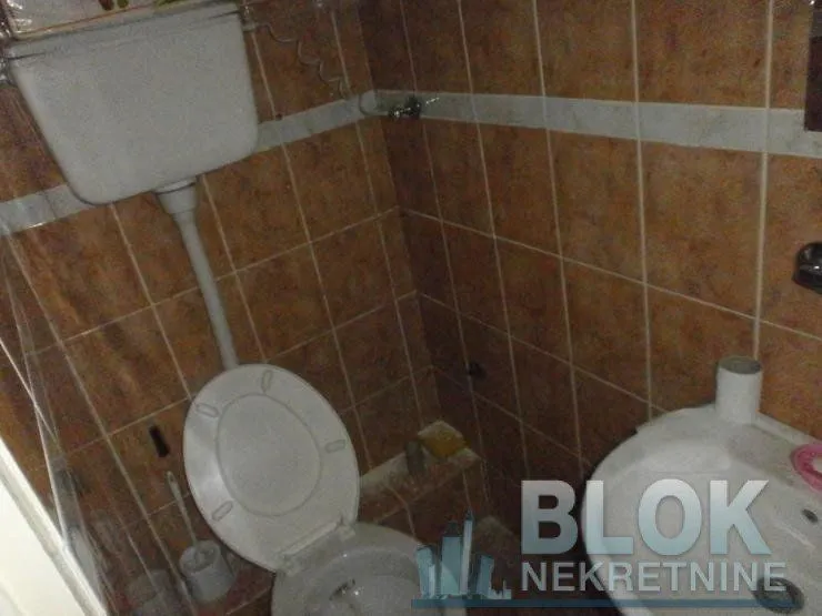 Smaller bathroom tiled with ceramic tiles, featuring a toilet and washbasin.