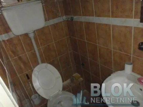 Smaller bathroom tiled with ceramic tiles, featuring a toilet and washbasin. - image 6