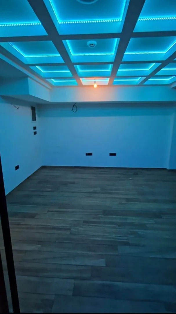 Empty room with a suspended ceiling and blue LED lighting.