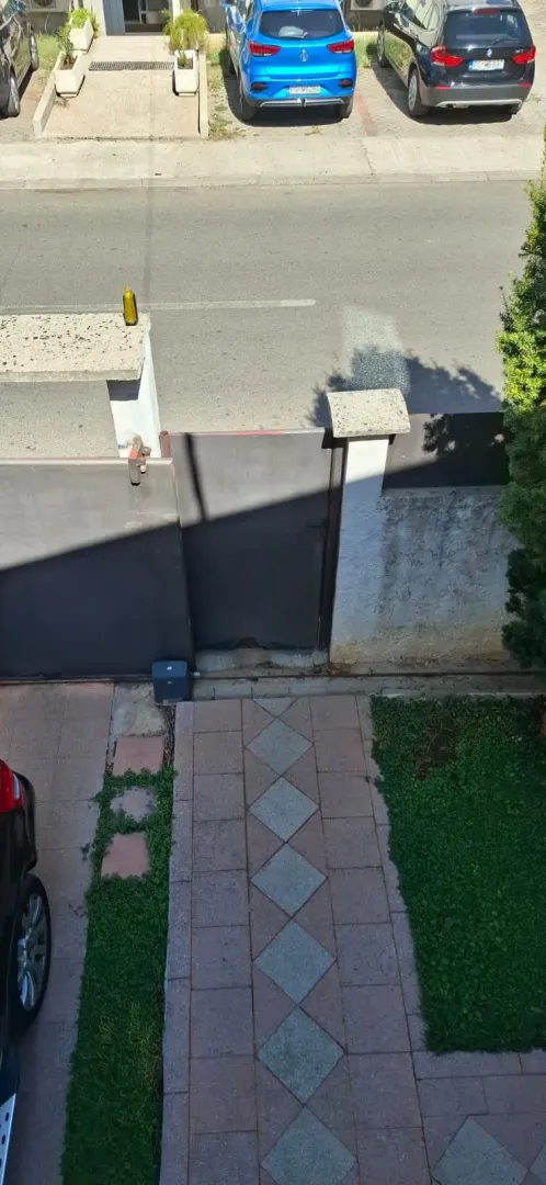 Pogled odozgo na dvorišnu stazu, kapiju i ulicu sa parkingom.