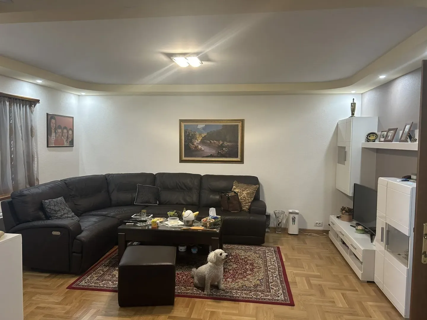 Spacious living room with a leather sectional sofa and a TV unit.