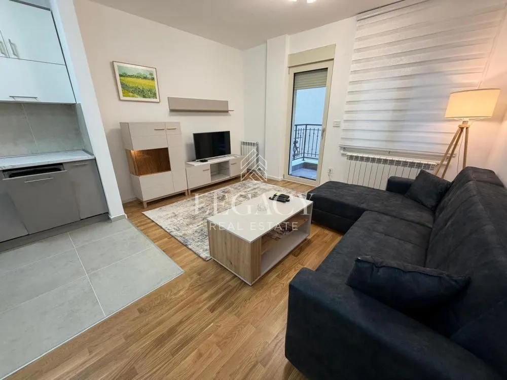 Living room with a sofa, TV, and access to the balcony.