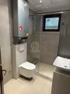 Modern bathroom with a walk-in shower, toilet and water heater. - image 11