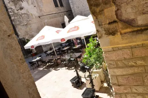 Paved courtyard in the old town with a cafe terrace and stone walls. - image 19