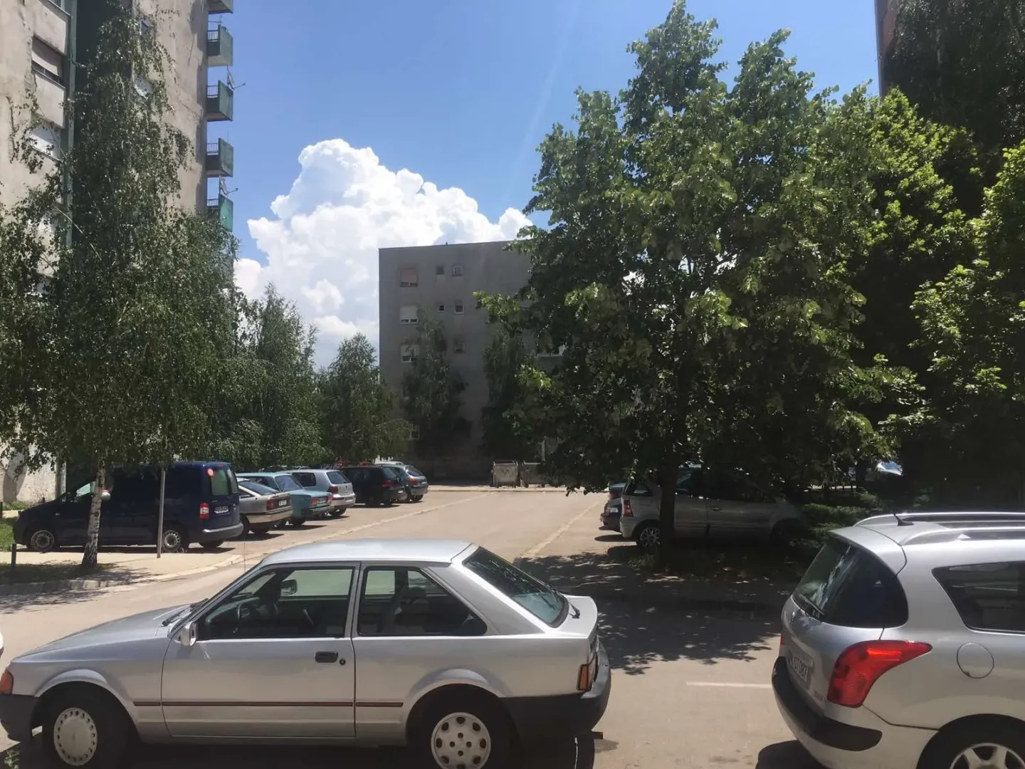 View of the parking lot in front of the residential building with trees.