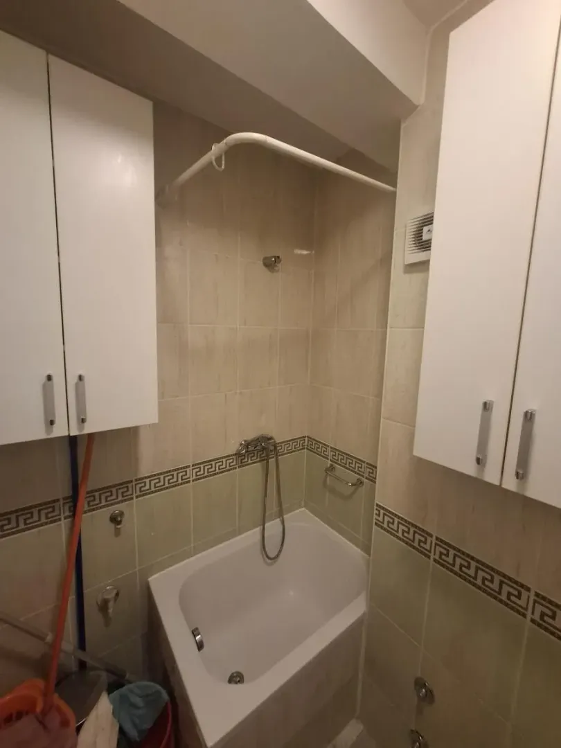 Kupatilo opremljeno kadom i belim zidnim ormarićima.