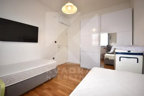 Children's bedroom with two beds, a white wardrobe, and a wall-mounted TV. - image 11