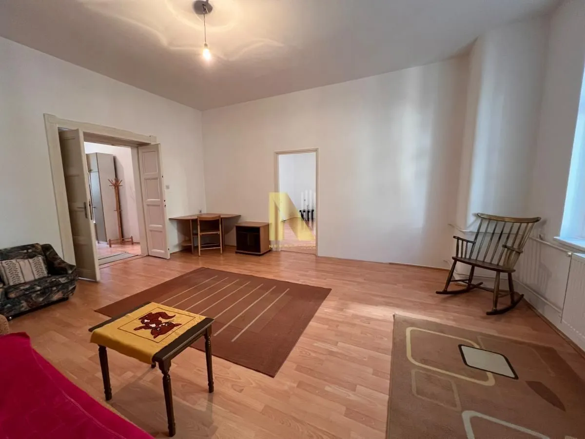 Spacious living room with wooden flooring, rugs, and furniture.