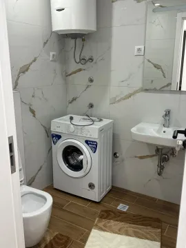 Small bathroom with a sink, washing machine, toilet, and water heater. - image 7
