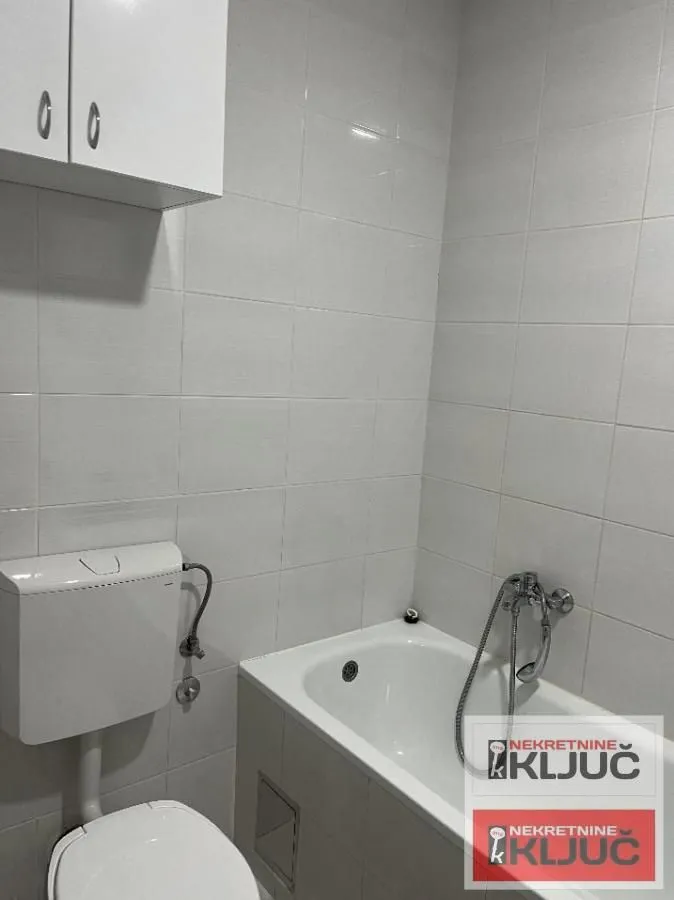 Manje kupatilo sa kadom, wc šoljom i zidnim ormarićem.