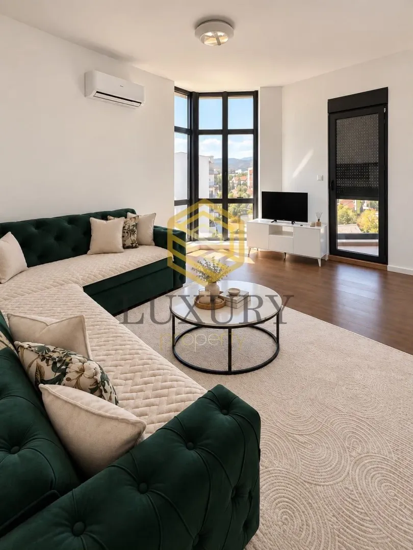 Bright living room with a green sectional sofa and large windows.