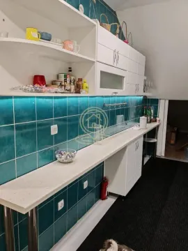 Small kitchen with white cabinets and turquoise wall tiles. - image 10