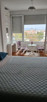 Nameštena spavaća soba sa krevetom i malim kutkom za sedenje pored prozora. - image 10