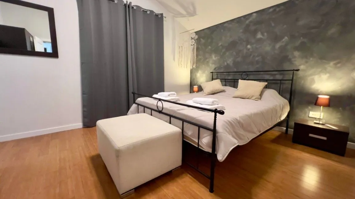 A furnished bedroom with a double bed, bedside tables, and a wardrobe.