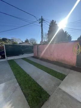 Concrete driveway with grass strips in front of a gate and yard wall. - image 3