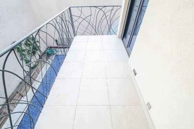 Manji popločani balkon sa ukrasnom metalnom ogradom i izlazom iz stana.