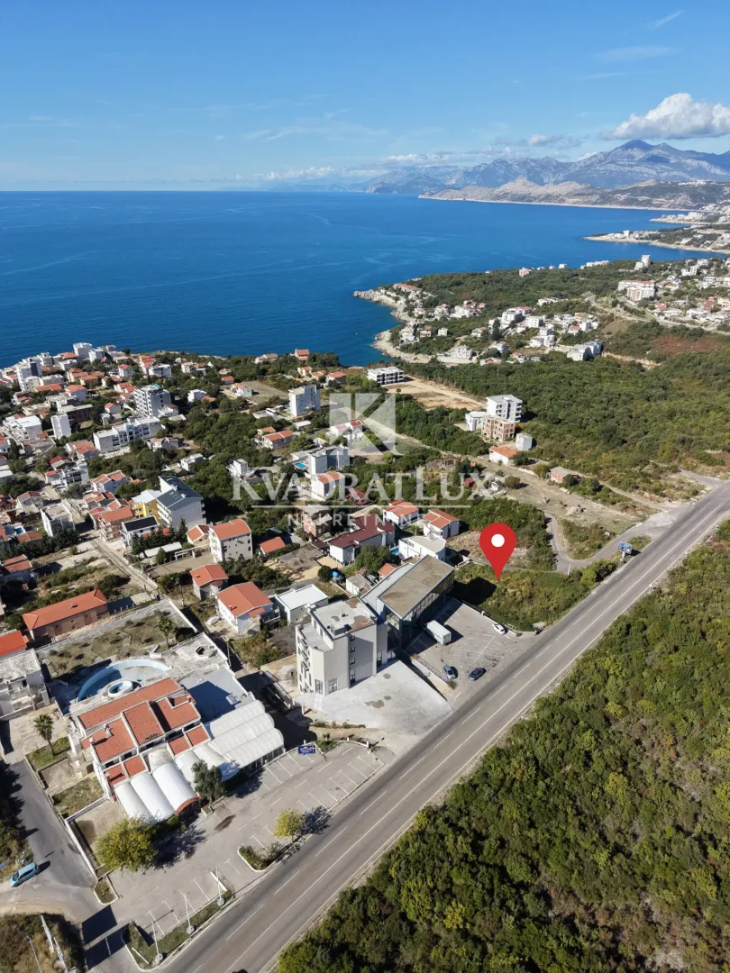 Pogled iz vazduha na priobalno naselje sa pogledom na more i planine u pozadini.