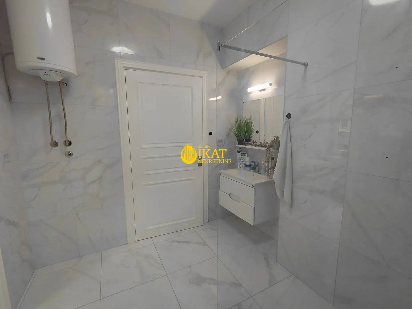 Modern bright bathroom with marble tiles, a white sink, and a built-in water heater.