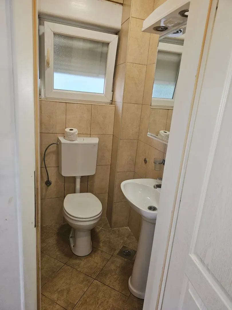 Small bathroom with a toilet, washbasin, and a window.