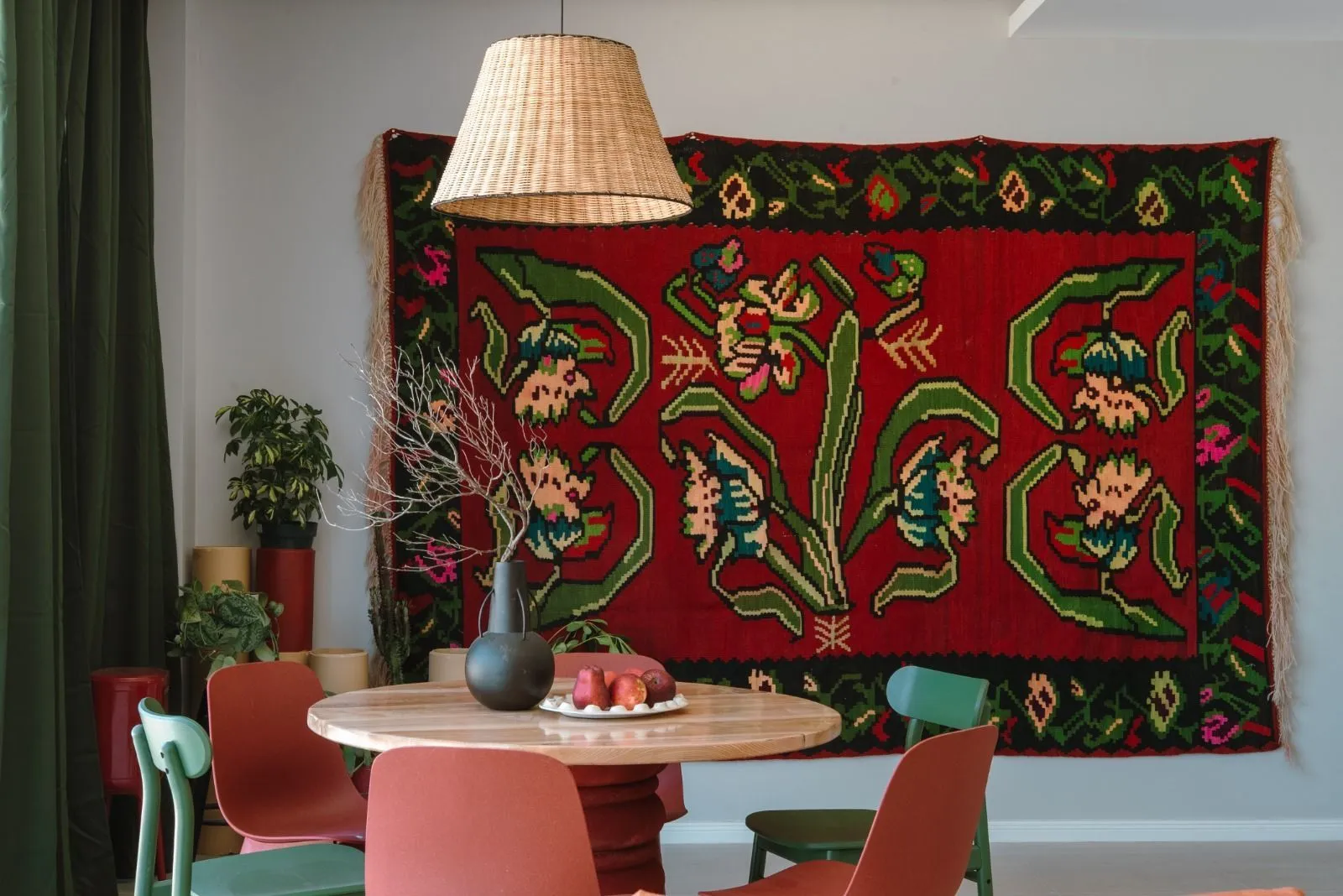 Dining area with a round table and a traditional rug on the wall.