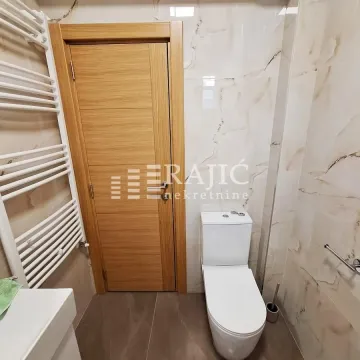 Small bathroom with toilet, wooden door, and white radiator. - image 9