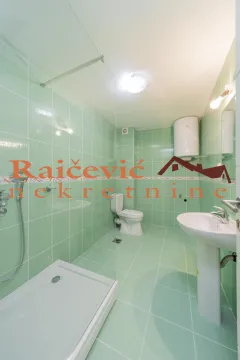 Kupatilo obloženo zelenim pločicama sa tuš kabinom, umivaonikom i toaletom. - image 11