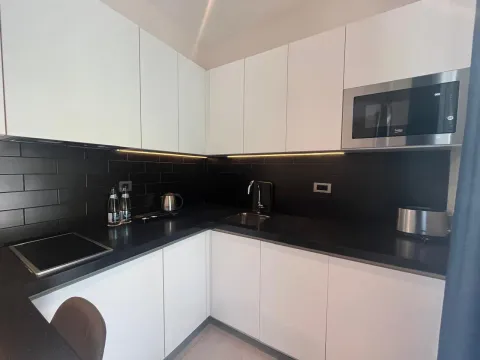 Moderna kuhinja sa bijelim elementima i crnom radnom površinom. - image 4