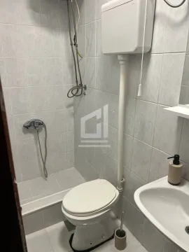 Small bathroom with a shower cabin, toilet, and washbasin tiled with light tiles. - image 6