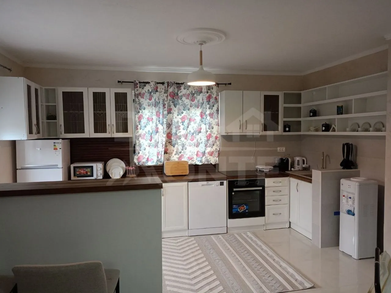 Fully equipped kitchen with white cabinetry and a window.