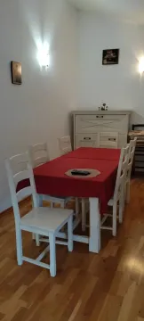 Dining table with white chairs and a red tablecloth. - image 10