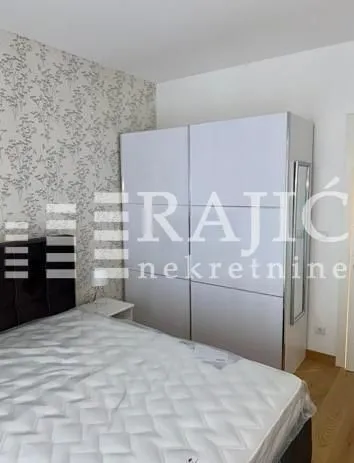 Nameštena spavaća soba sa velikim garderoberom i bračnim krevetom.