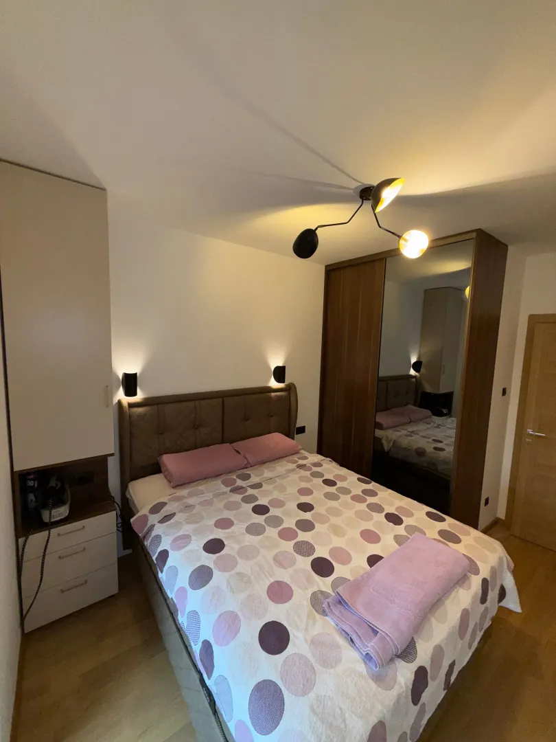 Spavaća soba sa bračnim krevetom, plakarom i noćnim lampama.