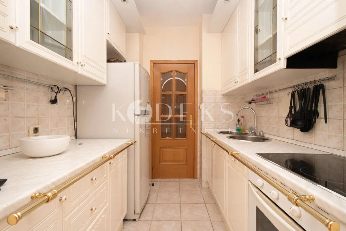 Kitchen equipped with white cabinets, built-in appliances, and a refrigerator.