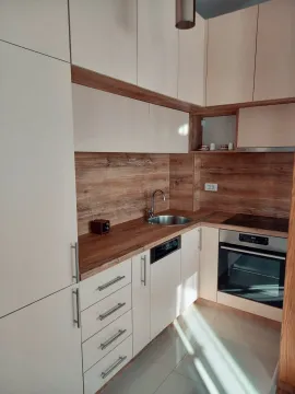 Modern kitchen with white cabinets and a wooden countertop. - image 2