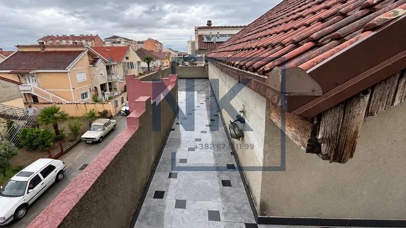 Tiled terrace with a view of surrounding buildings and the street.