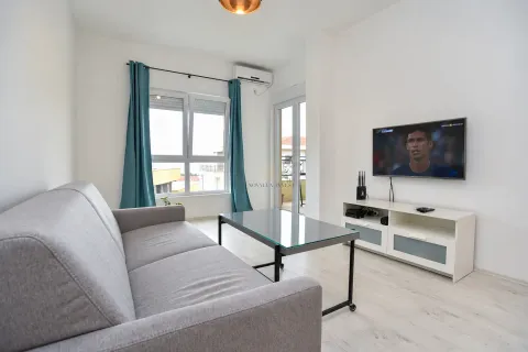 Living room with a gray sofa, glass coffee table, and a wall-mounted TV. - image 5