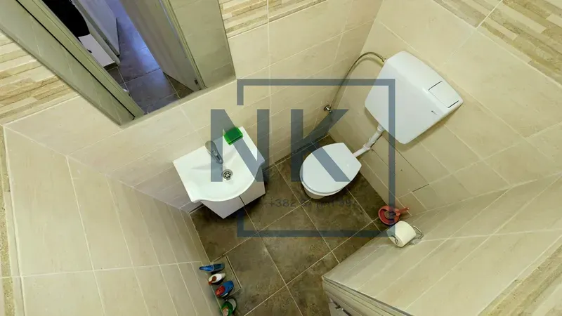 Small bathroom with a sink and toilet tiled with ceramic tiles.
