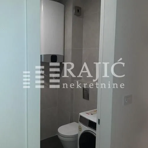 View of the bathroom with a toilet, washing machine, and water heater.