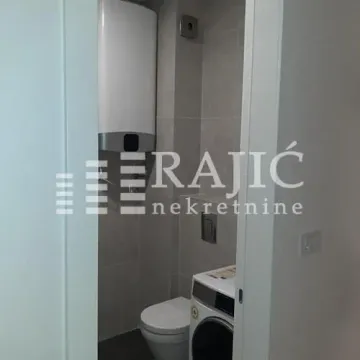 View of the bathroom with a toilet, washing machine, and water heater. - image 13