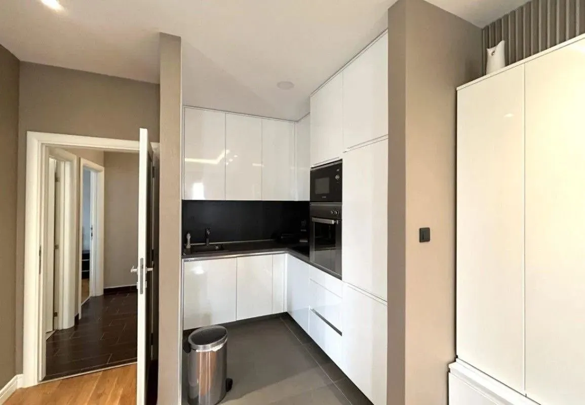 Modern kitchen with white cabinetry and built-in appliances.
