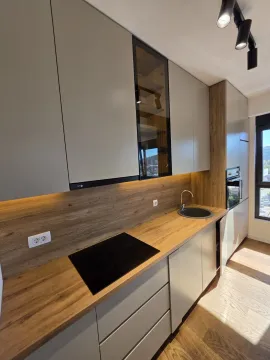 Modern kitchen with grey cabinets, wooden countertop and built-in appliances. - image 2