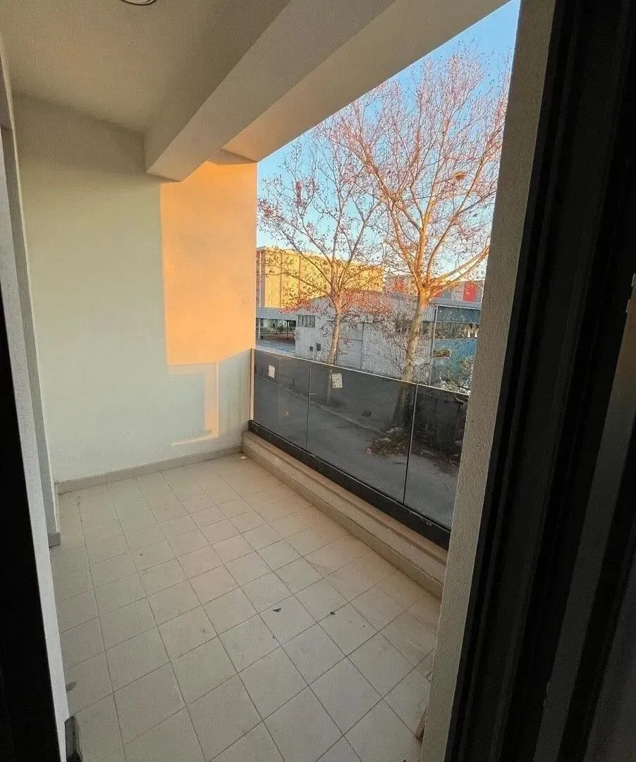 Empty covered terrace with glass railing and street view.