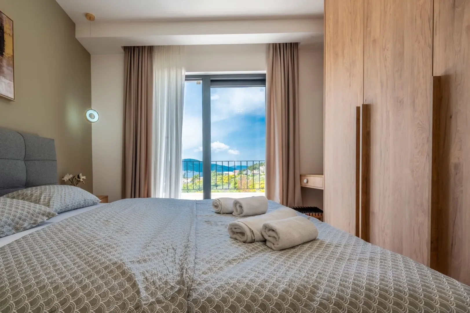 Svijetla spavaća soba sa francuskim krevetom i izlazom na balkon.