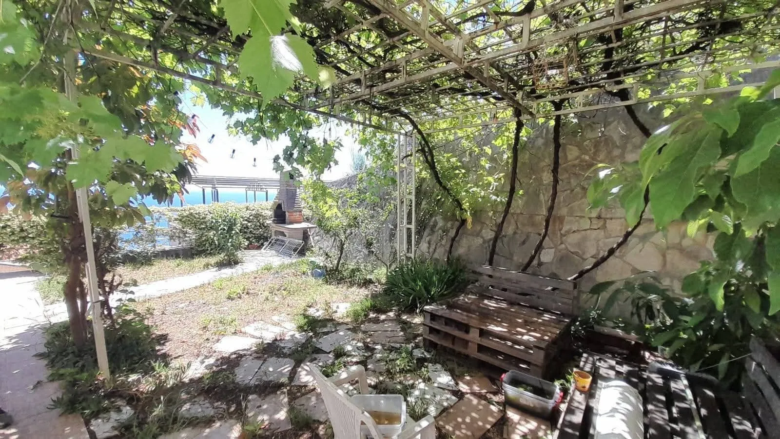 Yard with a covered terrace, barbecue, and sea view.