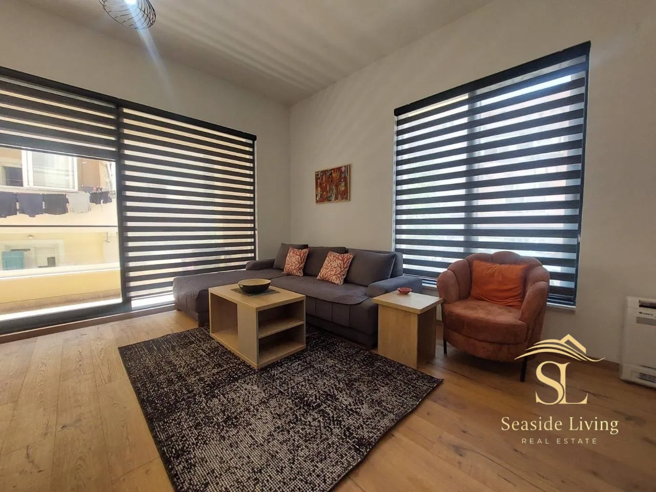 Living room with a sofa, coffee table, and windows with blinds.