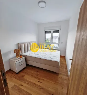 Manja spavaća soba sa bračnim krevetom, noćnim stočićem i prozorom. - image 11
