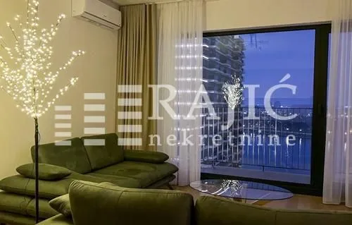 Furnished living room with a sofa and a view through a large window.