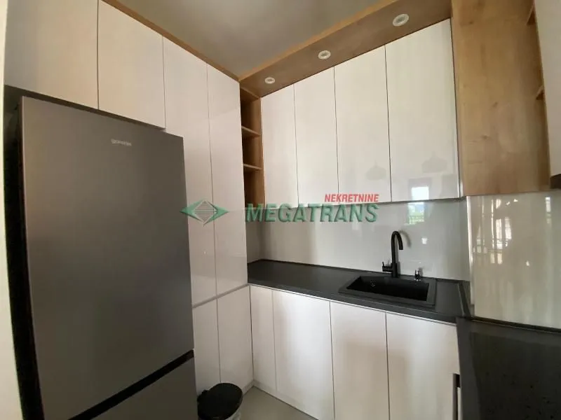 Modern kitchen with white cabinets and a grey refrigerator.
